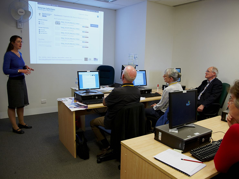 Volunteers with PC's watching trainer giving a presentation